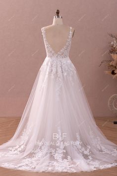 a white wedding dress with flowers on the skirt and sheer tulle overlays