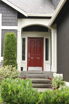 a red door sits in front of a house with steps leading up to the entrance