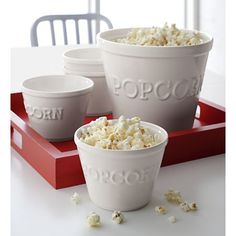 three white bowls filled with popcorn sitting on top of a red tray next to each other