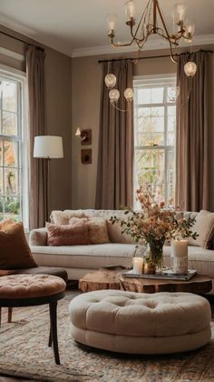 a living room filled with furniture and a chandelier hanging from the ceiling next to two windows