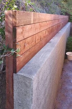 a concrete bench sitting next to a wooden fence