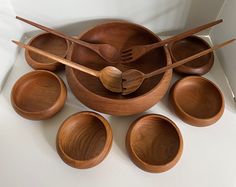 wooden bowls and spoons are stacked on top of each other with wood utensils in them