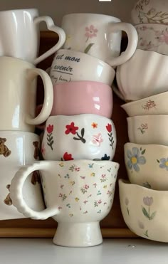 many cups and saucers are stacked on a shelf