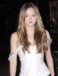 a woman with long hair wearing a white dress and posing for the camera at night