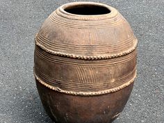 an old brown vase sitting on the ground