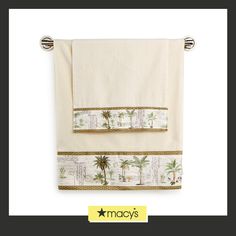 two towels with palm trees on them are hanging from the side of a towel rack