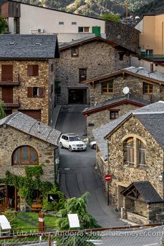 a car is parked in the middle of an alleyway between two buildings, with mountains in the background