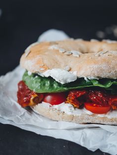 a bagel sandwich with tomatoes, lettuce and cheese