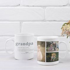 a coffee mug sitting next to a vase with flowers in it on a white table