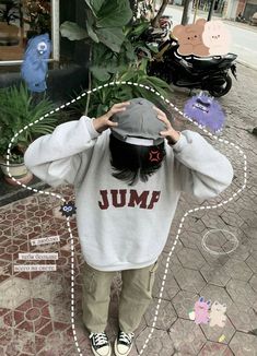 a person standing on the street with their hands behind their head, wearing a sweatshirt that says jump