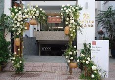 an entrance to a building with white flowers and greenery on the front door area