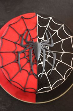 a spiderman cake is decorated with black icing and red frosting on a plate