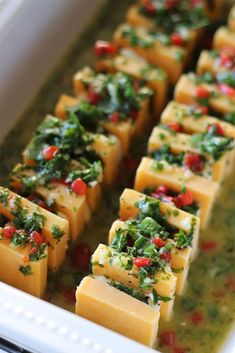 several pieces of tofu in a white dish with herbs on top and garnishes on the side