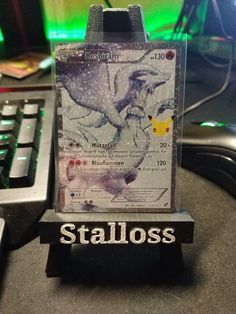 a close up of a pokemon trading card on a desk next to a computer keyboard