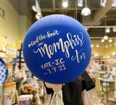 a person holding up a blue balloon with the words memorial written on it in front of a store