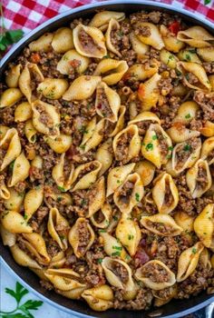 a skillet filled with pasta and ground beef on top of a checkered table cloth