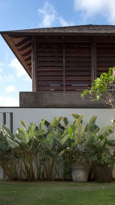 two large planters sitting on the side of a white wall next to a green lawn