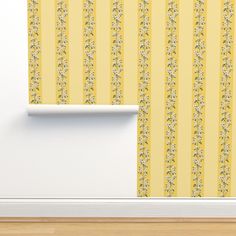 an empty room with yellow striped wallpaper and a white shelf on the floor in front of it