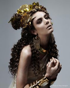 a woman with long curly hair and gold jewelry on her head is posing for the camera