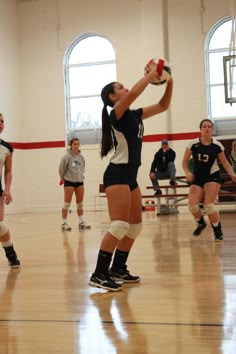 a group of women playing volleyball in a gym