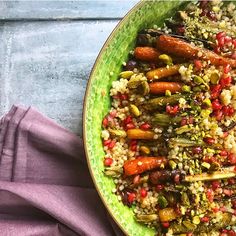 a green bowl filled with rice and vegetables on top of a purple cloth next to a spoon