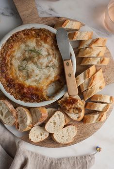 a plate with bread and cheese on it next to a knife, fork and spoon