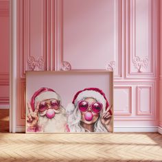 a pink room with two framed photos on the wall and santa claus's hat