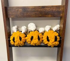 three stuffed animals sitting on top of a wooden shelf in front of a white wall