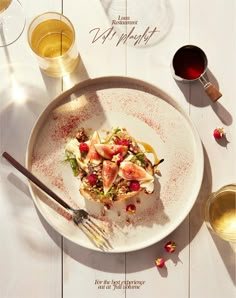 a white plate topped with food next to wine glasses