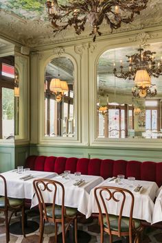 a dining room with tables and chairs, chandeliers hanging from the ceiling and windows