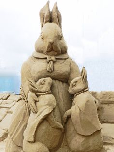 a sand sculpture of two rabbits and a rabbit holding an egg in it's lap