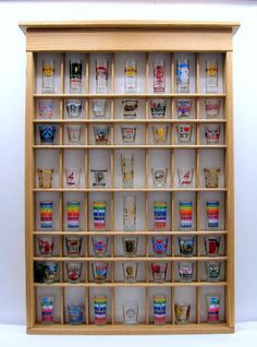 a wooden shelf filled with glasses on top of a white floor next to a wall