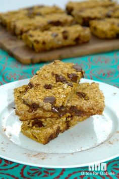 chocolate chip granola bars stacked on top of each other in front of a cutting board