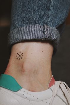 a person with a small cross tattoo on their left side ribcading the ankle