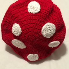 a crocheted red dice with white dots sits on top of a tablecloth