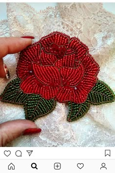 a woman's hand holding an embroidered rose