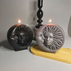 two candles sitting next to each other with faces on them and one candle in the shape of a sun