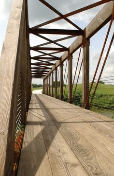 an old wooden bridge with flowers growing on the side and grass in the back ground