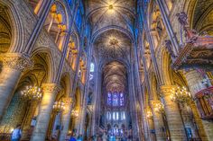 the inside of a large cathedral with chandeliers and stained glass windows in it