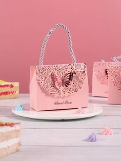 two pink bags sitting on top of a table next to a slice of birthday cake