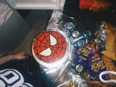 a spiderman cake sitting on top of a table next to cans and candy bars