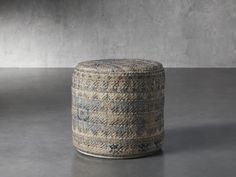 a large round ottoman sitting on top of a cement floor next to a gray wall