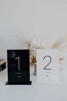 two black and white clocks sitting on top of a table next to a vase with flowers