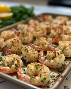 a pan filled with shrimp and garnish next to lemon wedges