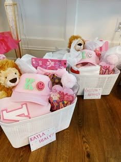 two teddy bears are sitting in baskets filled with items for a baby's first birthday