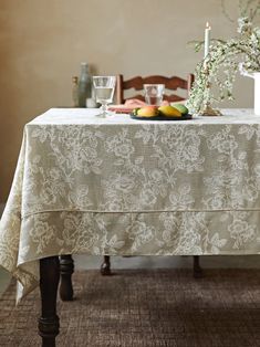 the table is set with fruit on it and flowers in vases next to it