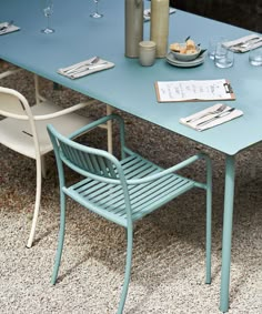 a blue table with two chairs next to it and some wine glasses on the table