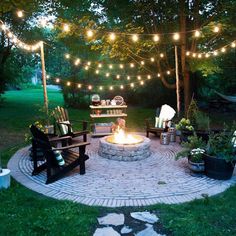 an outdoor fire pit with lights strung over it