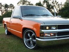 an orange pick up truck parked in the grass