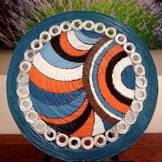 a blue and orange plate sitting on top of a wooden table next to a painting